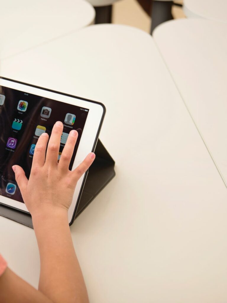 Lapsen sormet valitsemassa kuvaketta tabletin ruudulla.