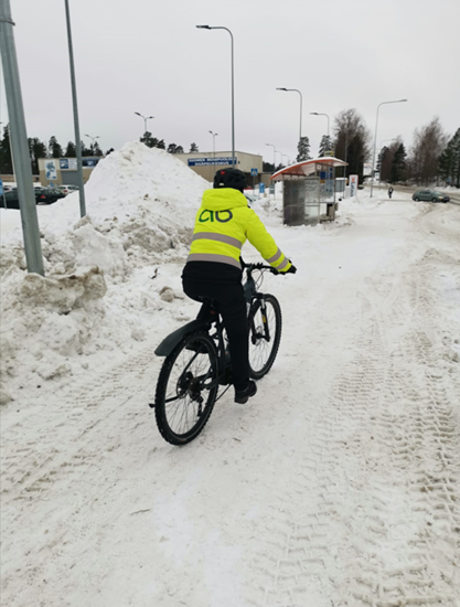 pyöräilijä ajaa lumista tietä pitkin