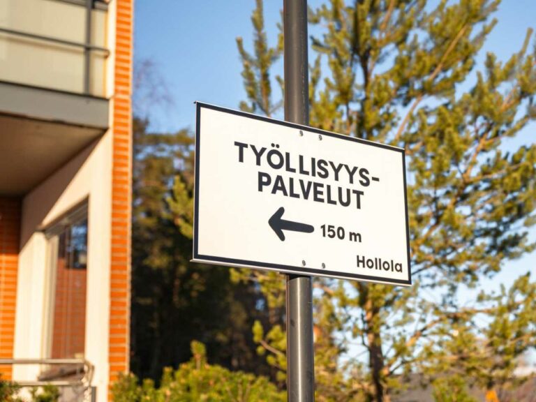 Opastekyltti, jossa teksti Työllisyyspalvelut 150 metriä sekä Hollolan kunnan logo.